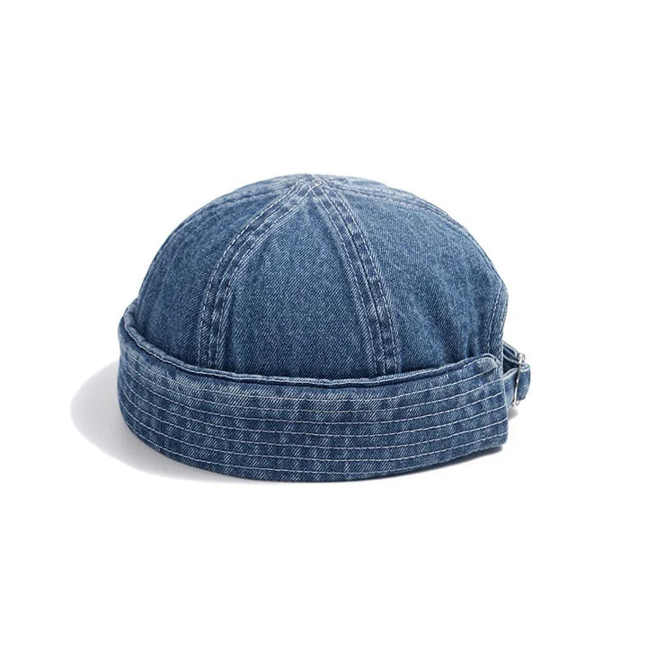 Blue denim brimless dock worker style cap with stitched detailing on white background