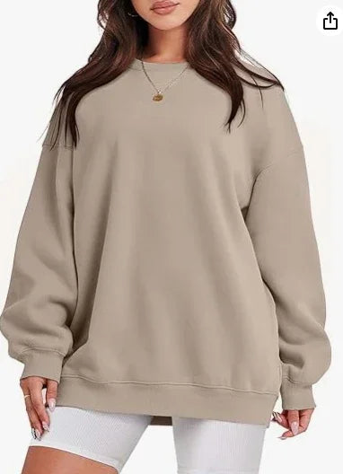 Woman wearing oversized beige sweatshirt with long sleeves and gold pendant necklace