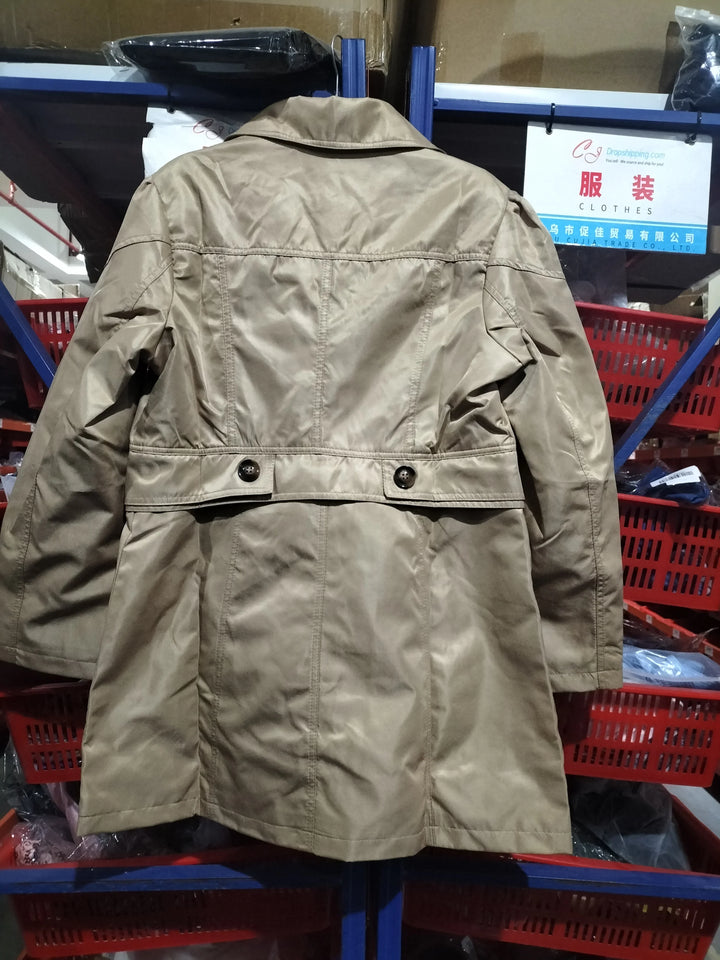 Beige trench coat hanging in a warehouse with red storage bins and clothing sign