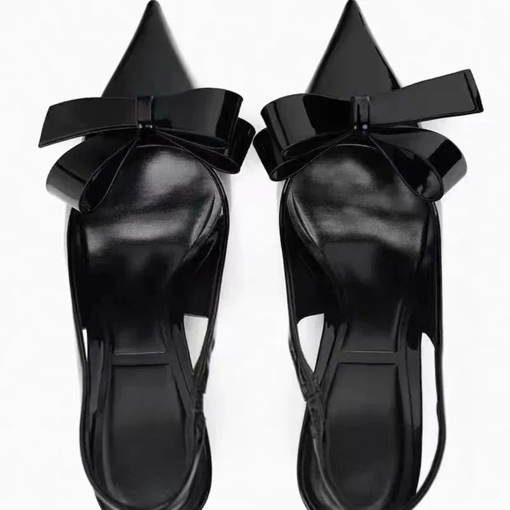 Pair of black patent leather pointed toe slingback flats with large decorative bows
