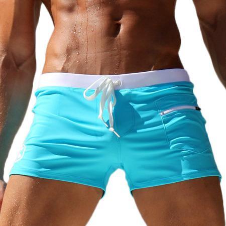 Close-up of muscular man wearing turquoise swim shorts with white waistband and zipper pocket