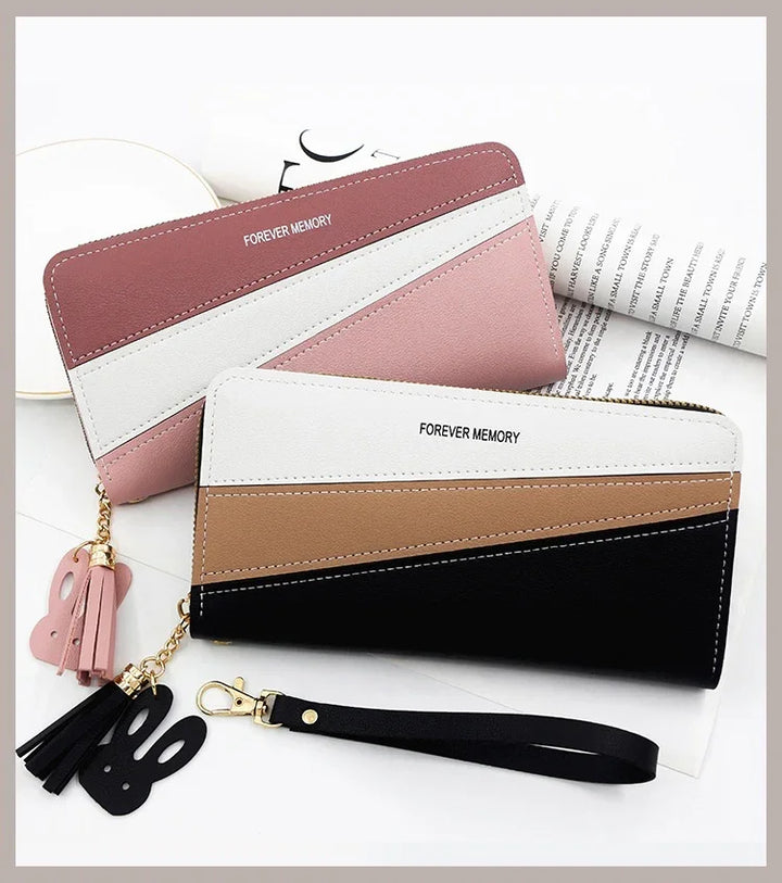 Two color-blocked wallets with tassel and bunny keychains, labeled Forever Memory, on a white surface