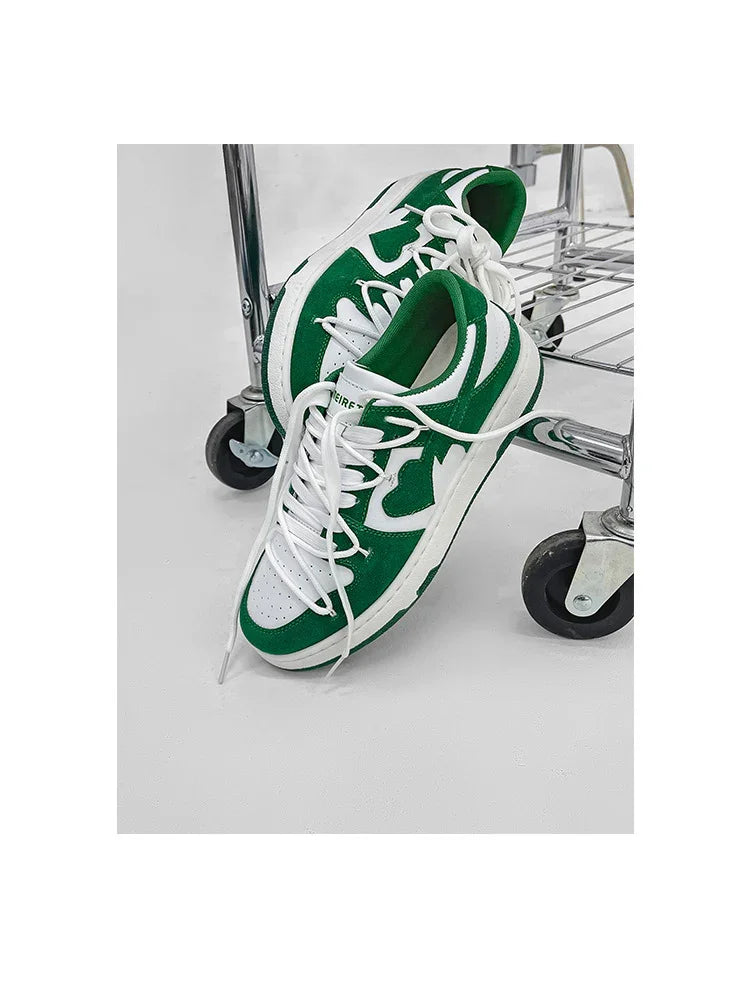 Green and white casual sneakers with white laces leaning against a metal cart wheel on a white floor