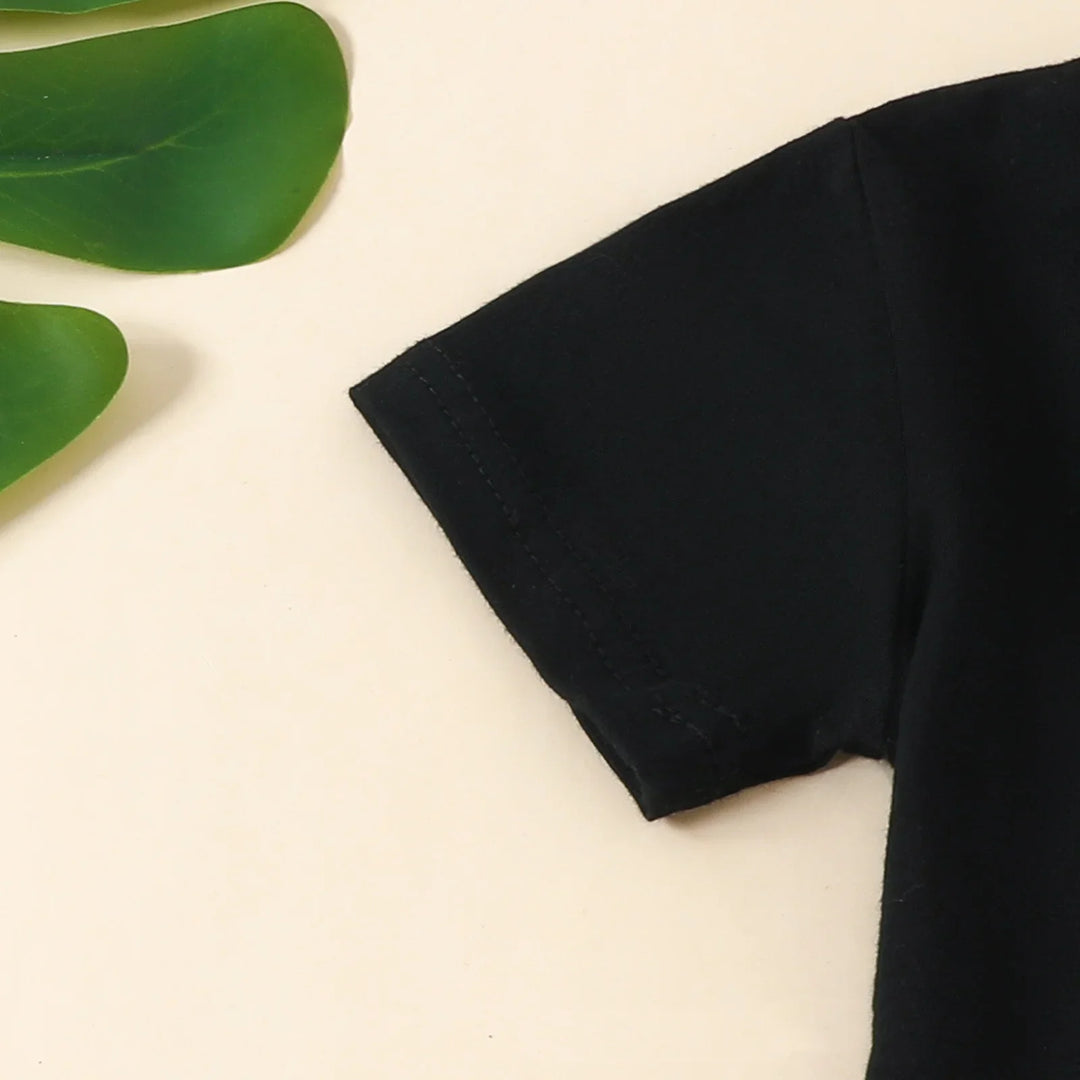Close-up of black cotton t-shirt sleeve on beige background with green leaves