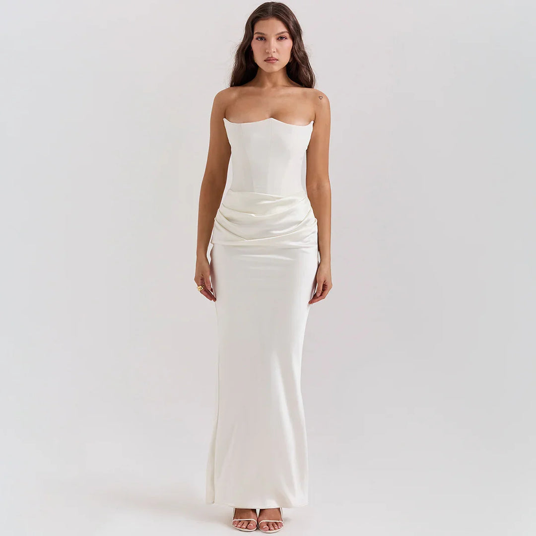 Woman wearing strapless white satin evening gown with draped waist detail on plain background