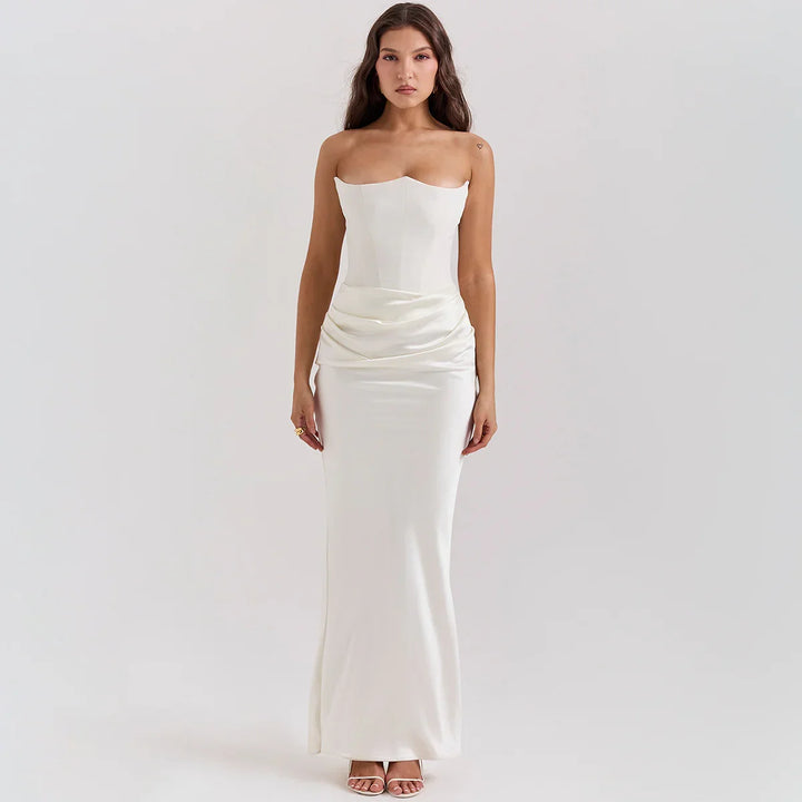 Woman wearing strapless white satin evening gown with draped waist detail on plain background