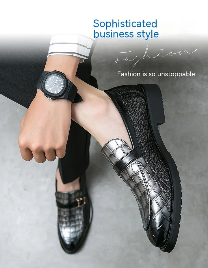Close-up of a person wearing black and silver crocodile pattern loafers and a black wristwatch, promoting sophisticated business style fashion