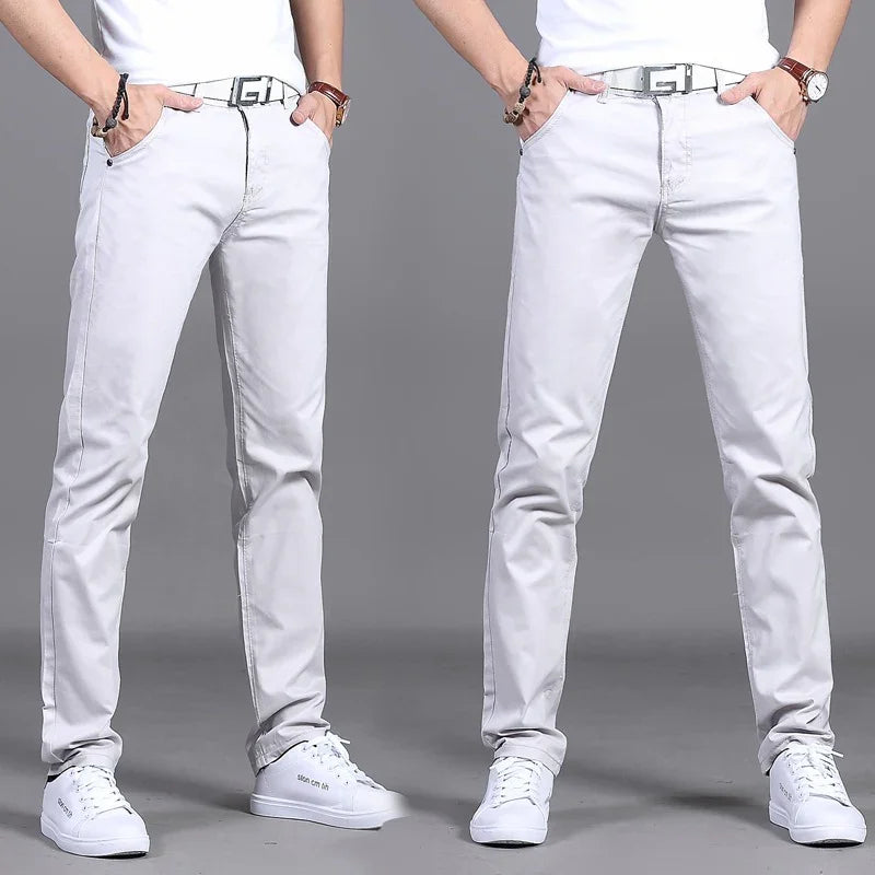 Men wearing slim fit light gray jeans, white sneakers, black bracelet, and brown wristwatch on gray background