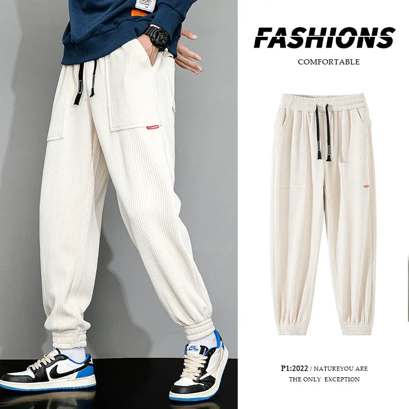 Beige casual corduroy jogger pants with elastic cuffs and black drawstrings, styled with sneakers