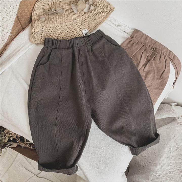 Dark gray toddler pants with elastic waist and rolled cuffs on white textured fabric