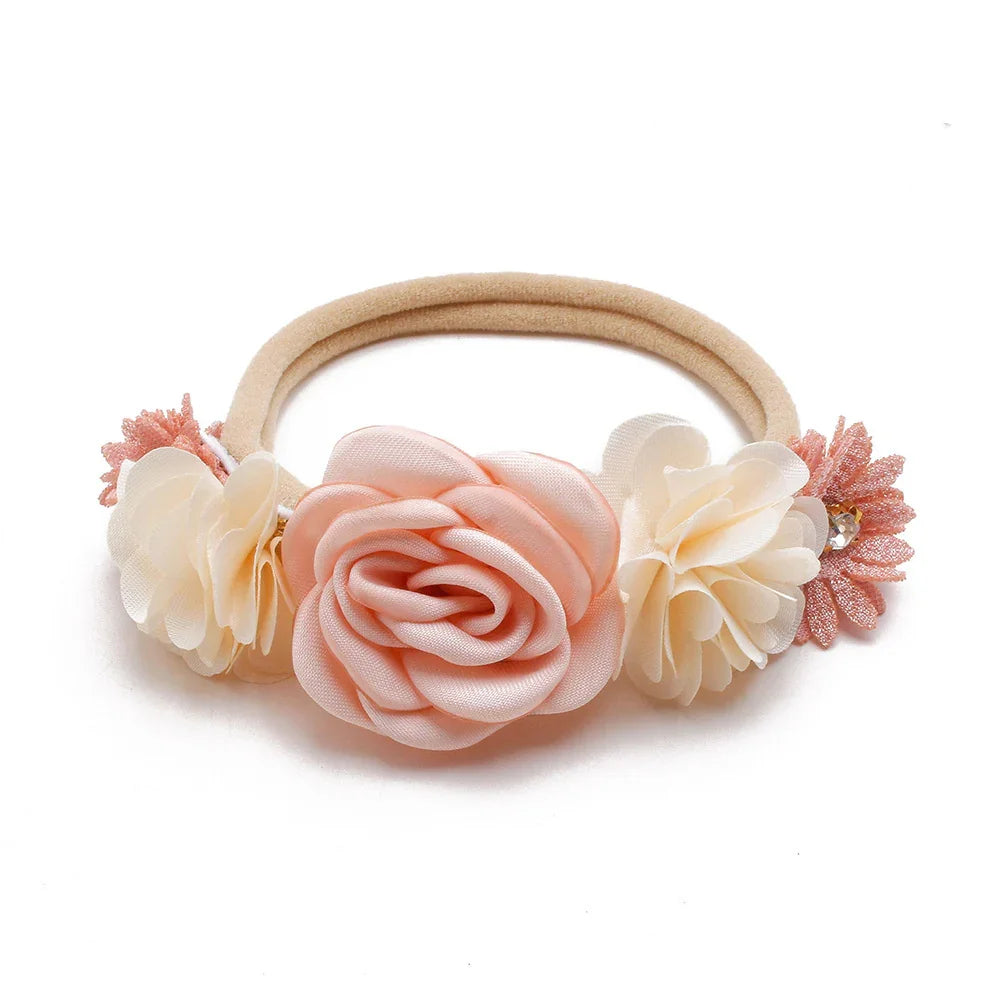 Beige elastic hairband with pink and cream fabric flower decorations on white background