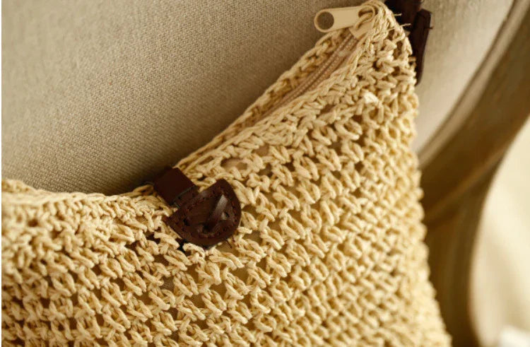 Close-up of beige handwoven crochet bag with a brown leather clasp on a tan fabric chair