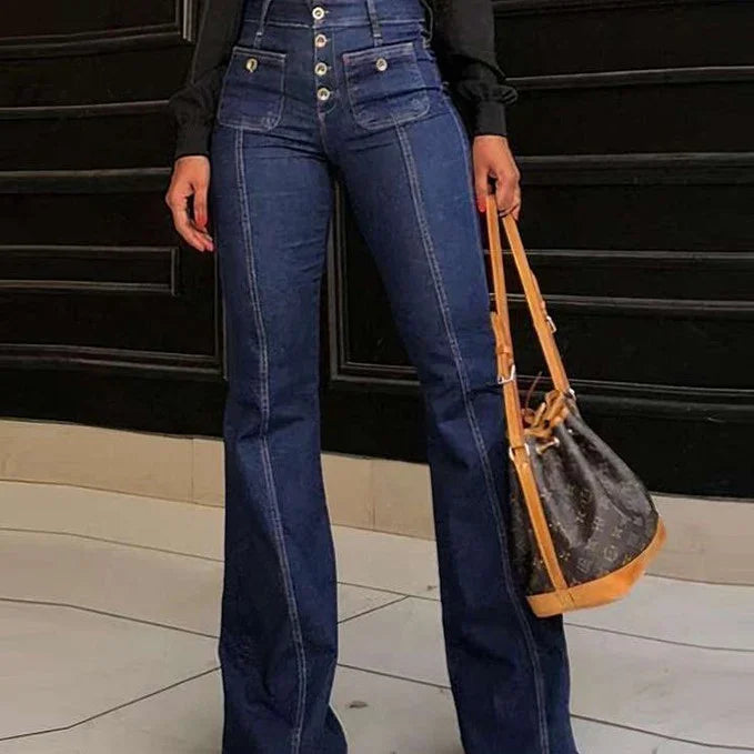 Person wearing high-waisted dark blue button-fly flared jeans with front stitching, holding designer bucket bag
