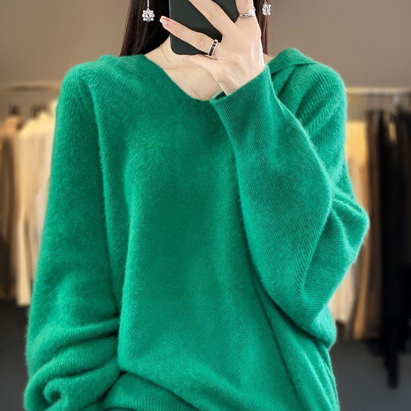 Woman wearing a soft green knit sweater taking a mirror selfie in a clothing store
