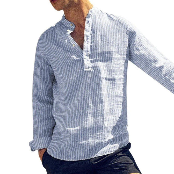 Man wearing light blue and white vertical striped linen shirt with band collar and black shorts