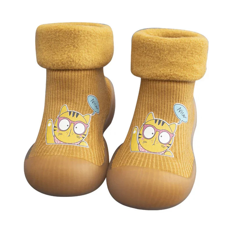 Yellow toddler slippers with soft cuff and cartoon cat design wearing glasses saying Nice
