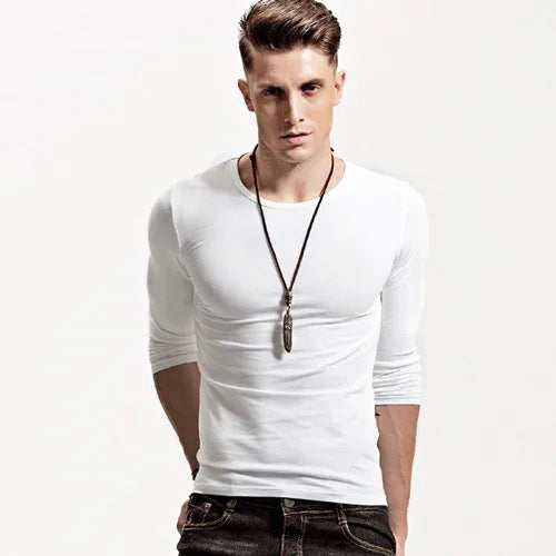 Young man wearing a fitted white long-sleeve shirt and black jeans with a pendant necklace