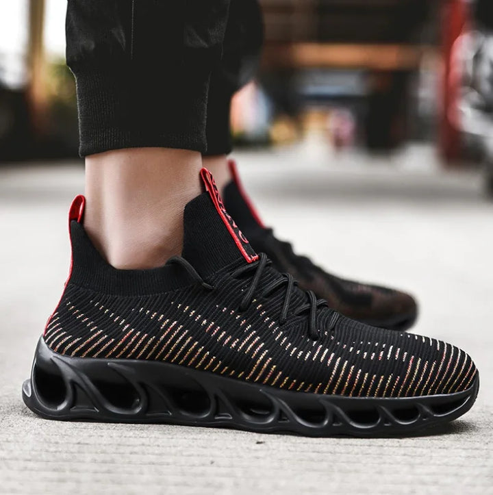 Black and red knit athletic sneakers with unique hollow black sole worn on concrete floor