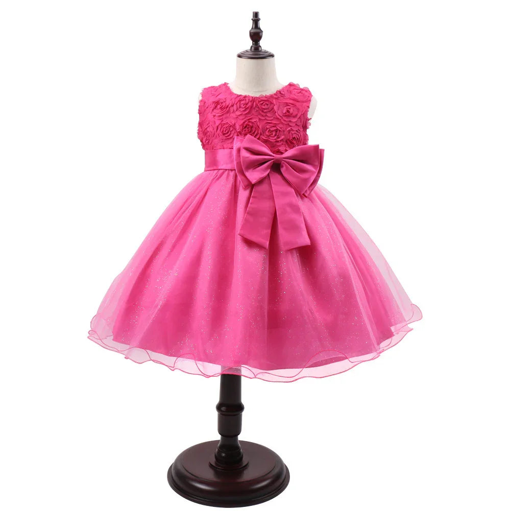 Bright pink girls party dress with floral top, large bow, and sparkly tulle skirt on mannequin