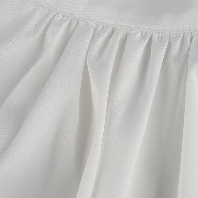 Close-up of white fabric with gathered stitching detail, showcasing texture and soft folds