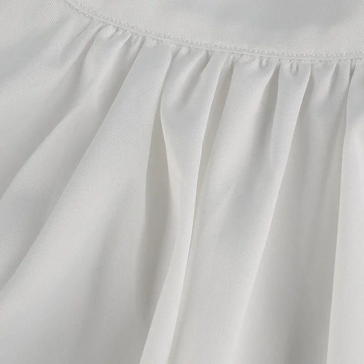 Close-up of white fabric with gathered stitching detail, showcasing texture and soft folds