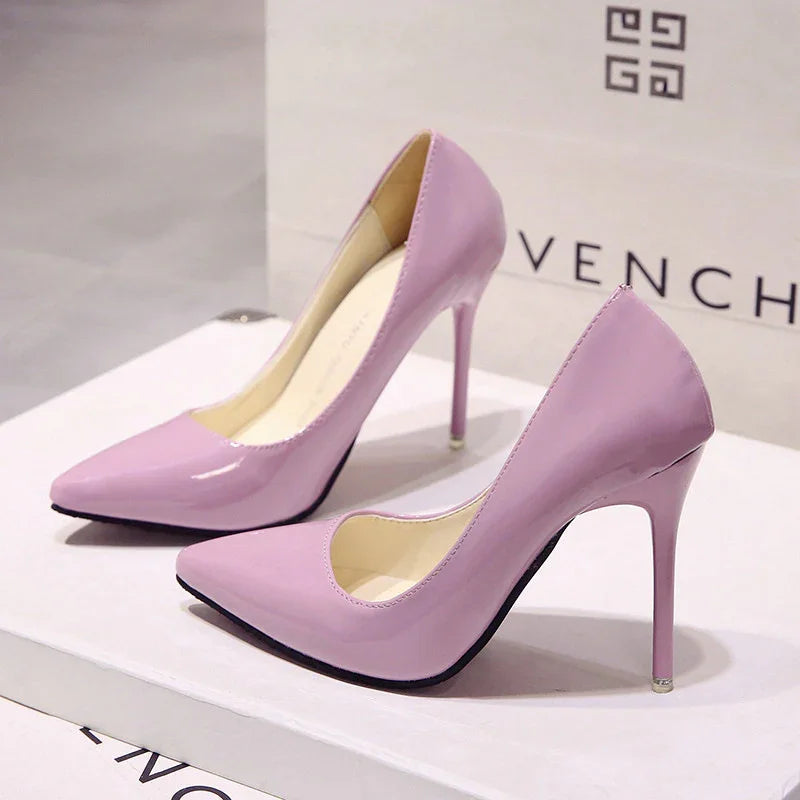 Pair of shiny lavender high heel stiletto shoes displayed on white box with Givenchy bag in background