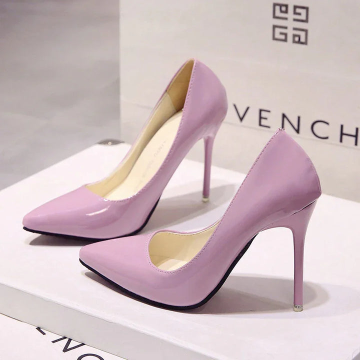 Pair of shiny lavender high heel stiletto shoes displayed on white box with Givenchy bag in background