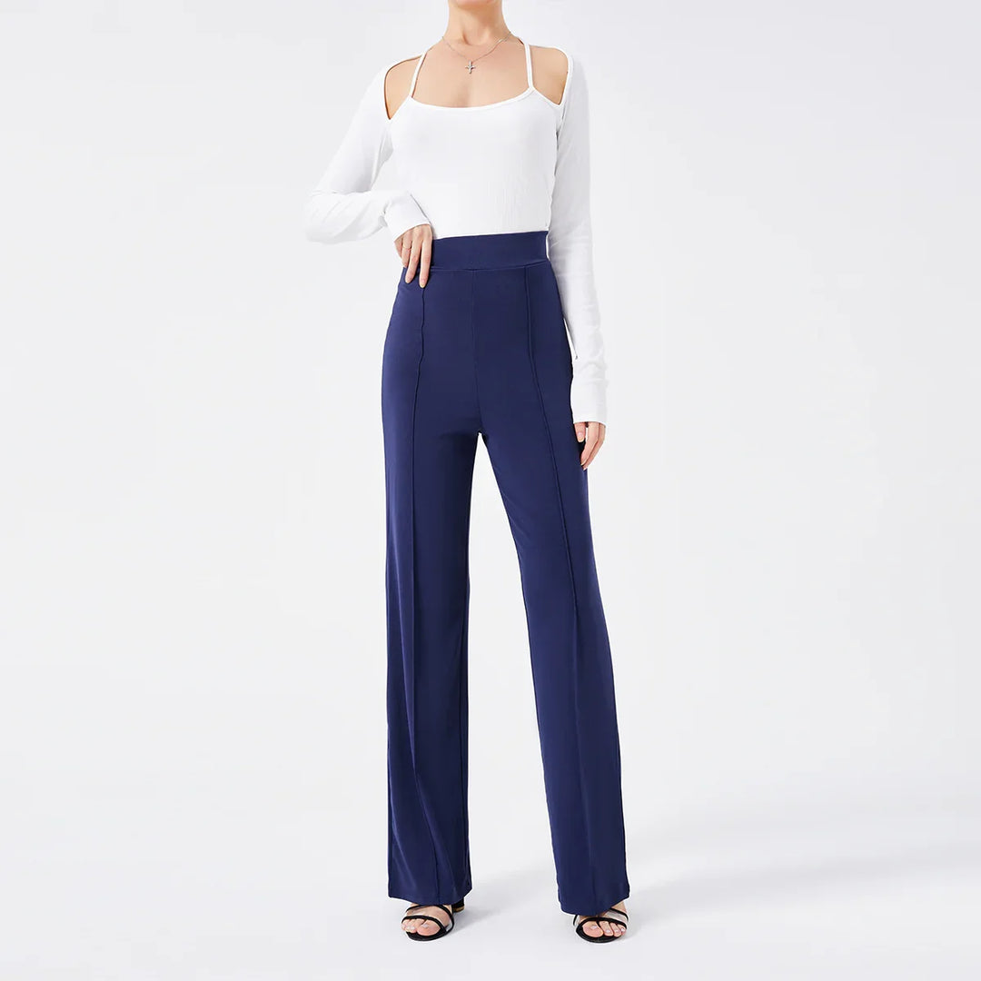 Woman wearing high-waisted navy blue wide-leg pants and white cold shoulder top with black sandals