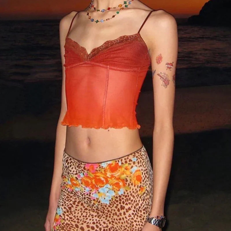 Woman wearing orange lace-trimmed cami top and floral leopard print skirt at sunset beach
