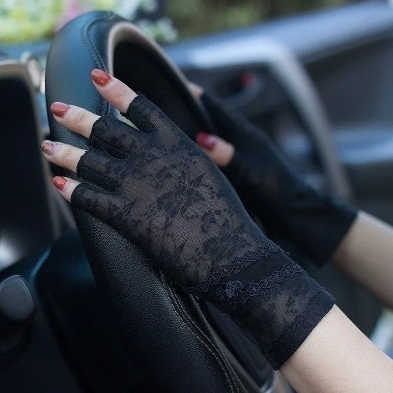 Hands wearing black lace fingerless gloves gripping a car steering wheel