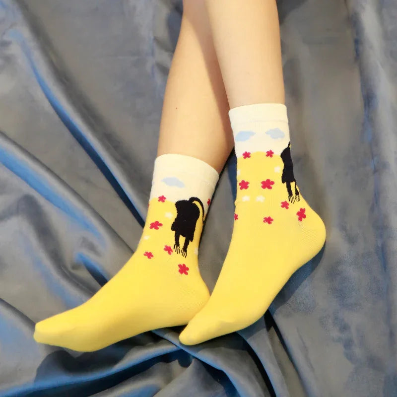 Close-up of feet wearing yellow socks with black cat and red flower patterns on gray fabric background