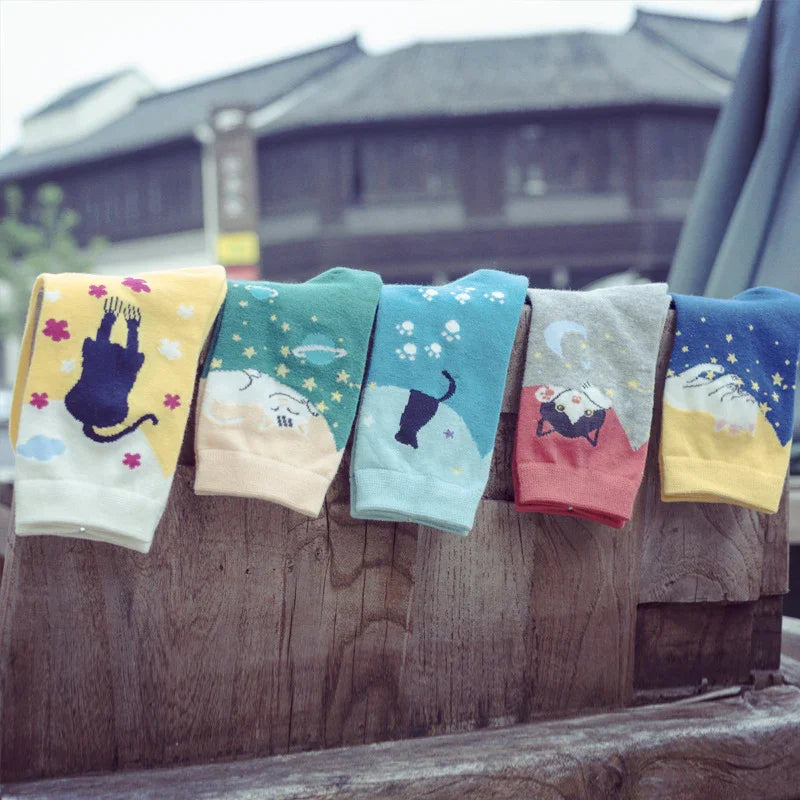 Colorful cozy socks with playful cat and star patterns displayed on a rustic wooden surface