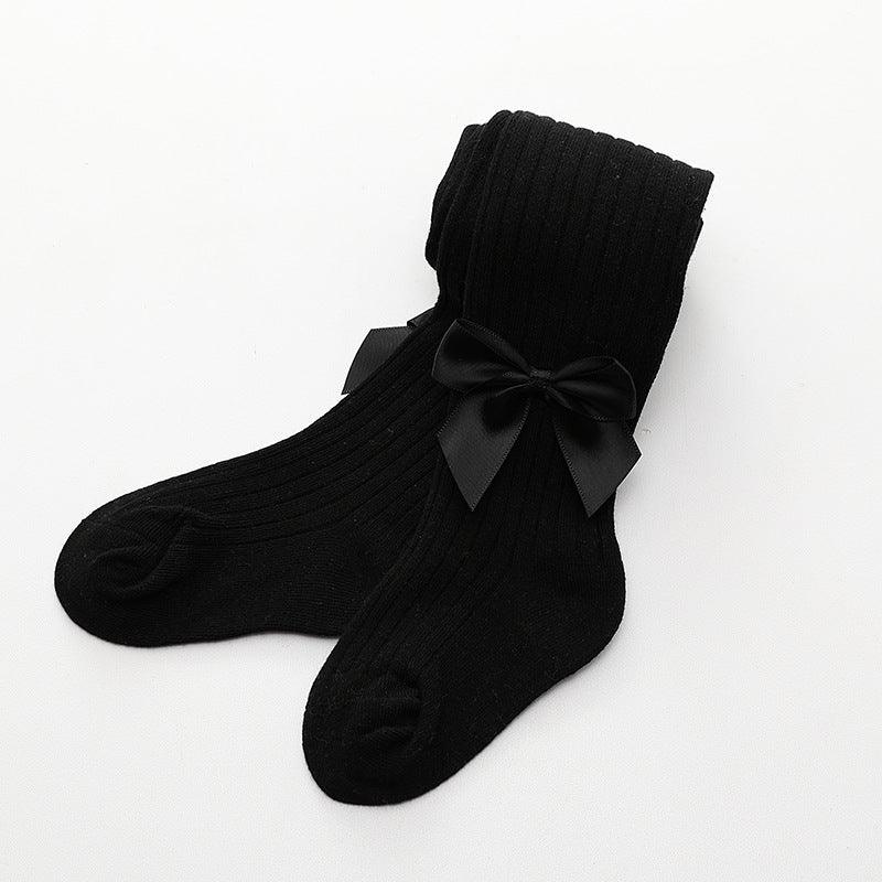 Pair of black ribbed knit socks with decorative black satin bows on a white background