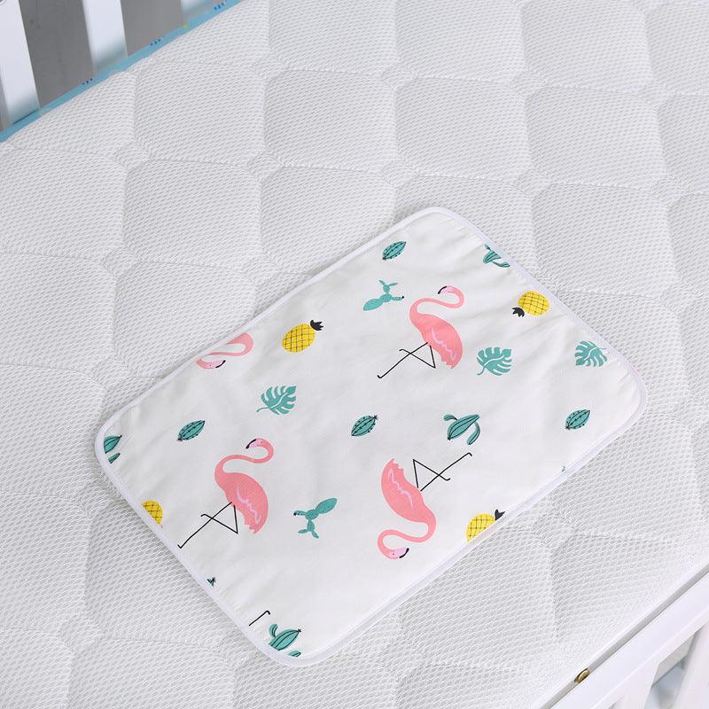 Baby changing pad with pink flamingo, pineapple, and green leaf prints on white mattress