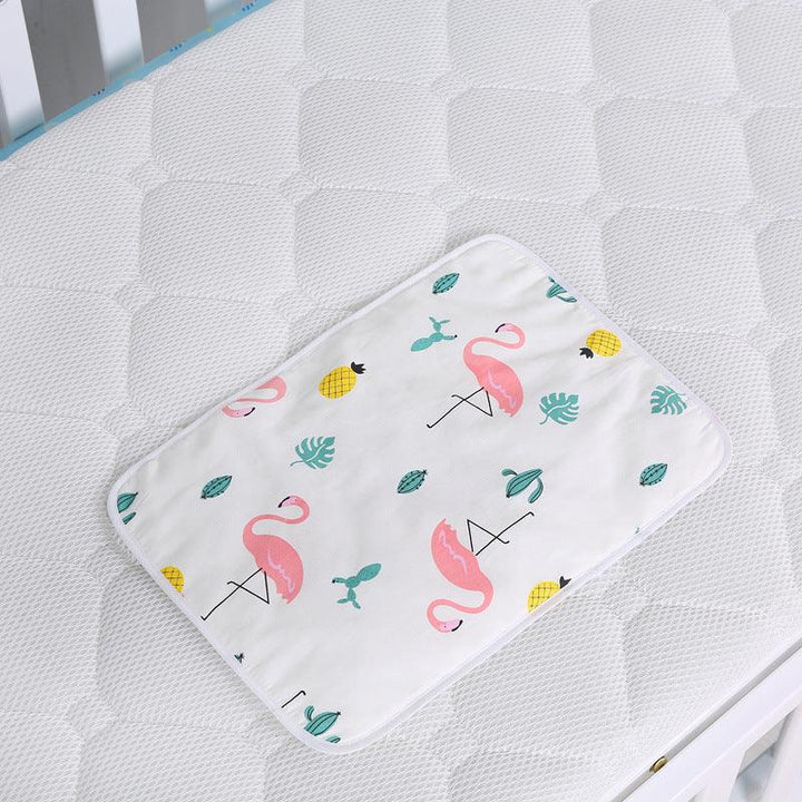 Baby changing pad with pink flamingo, pineapple, and green leaf prints on white mattress