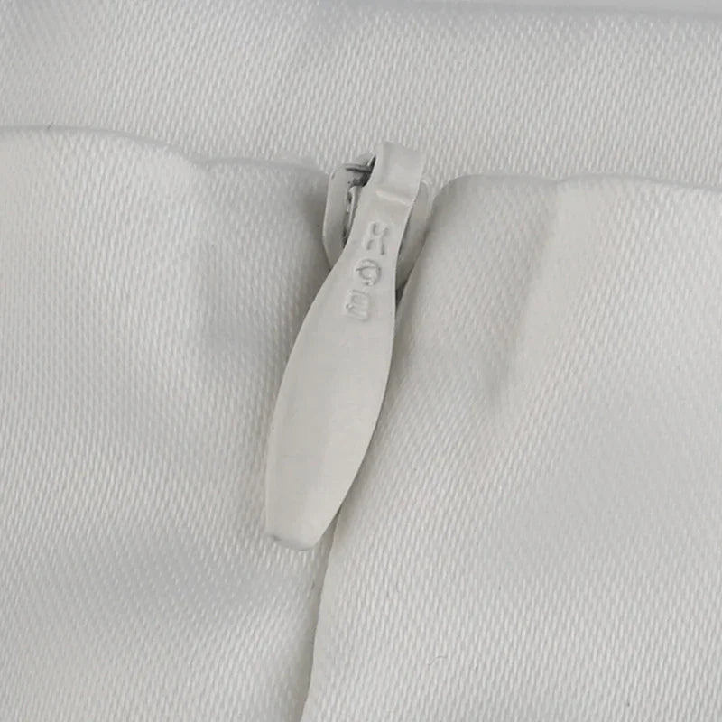 Close-up of a white RIRI brand zipper on textured white fabric