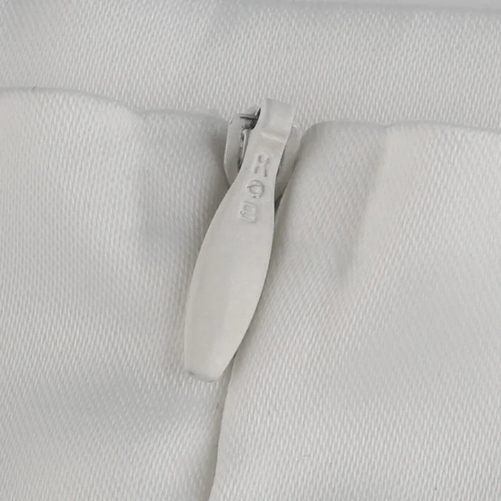 Close-up of a white RIRI brand zipper on textured white fabric