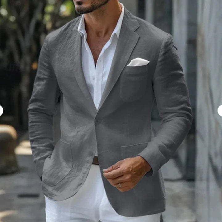 Man wearing a gray blazer with a white pocket square and white shirt outdoors