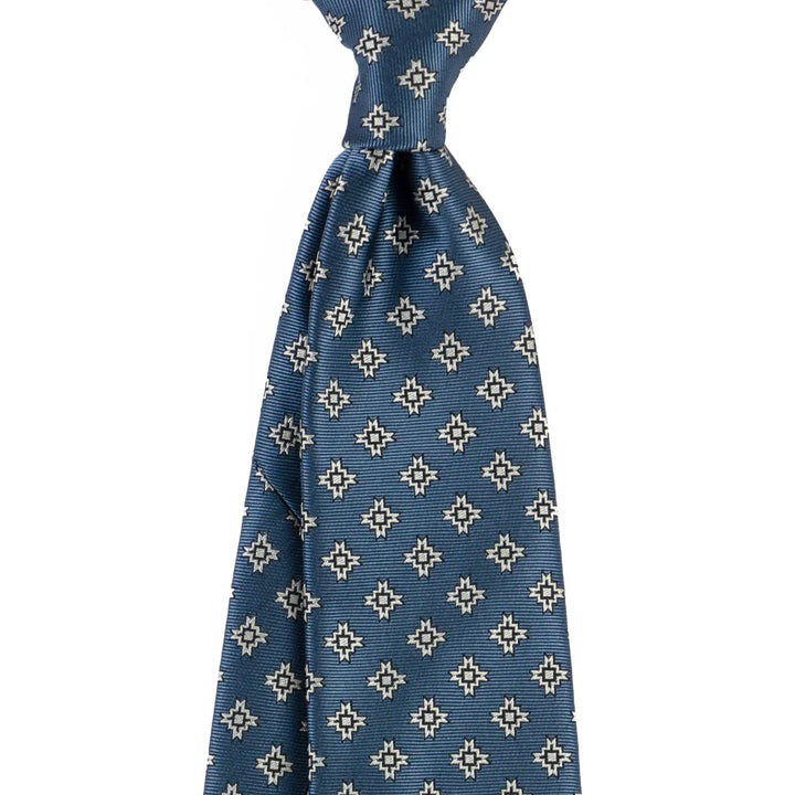 Blue silk tie with white and black geometric star pattern on white background