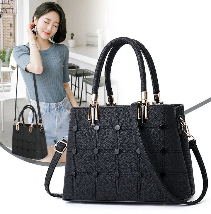Black textured leather handbag with gold hardware and shoulder strap shown on woman and alone