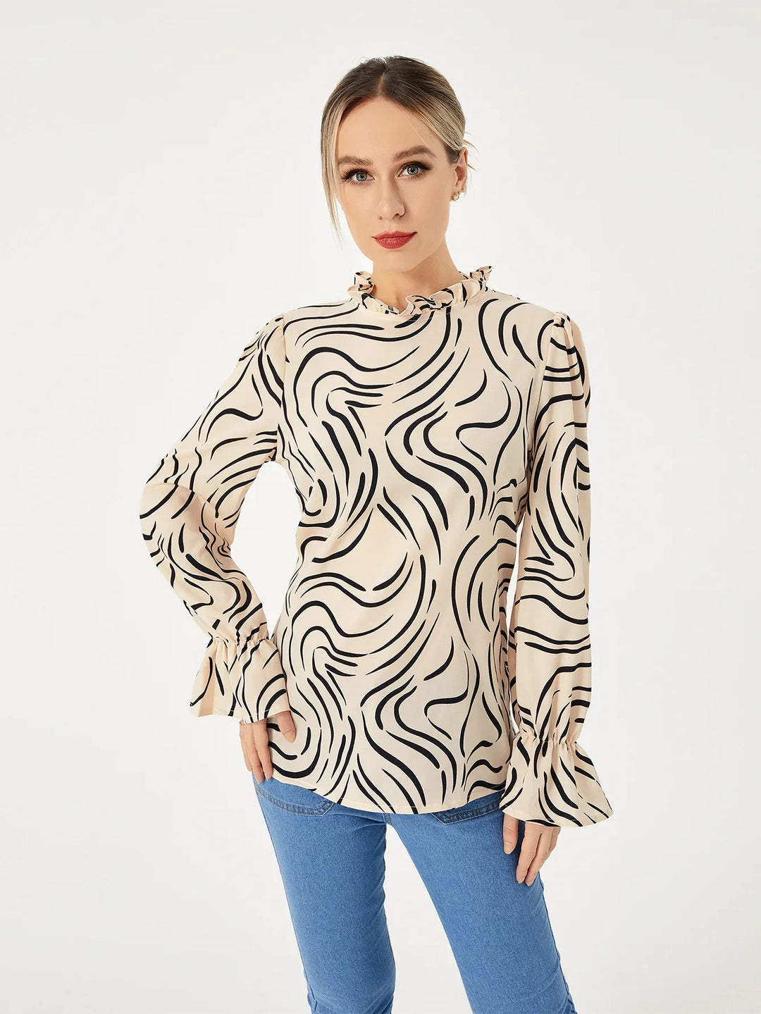 Woman wearing beige blouse with black abstract wavy print and ruffled sleeves, paired with blue jeans