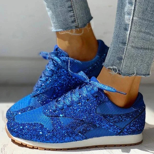Sparkling blue glitter sneakers worn with frayed denim jeans on light background