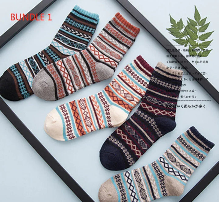 Bundle of five colorful patterned wool socks arranged in a black frame with green leaves