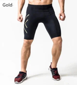 Man wearing black compression shorts with gold accents and red running shoes on white background