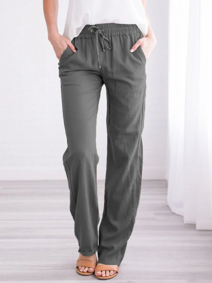 Woman wearing charcoal gray drawstring pants with pockets and sandals on wood floor