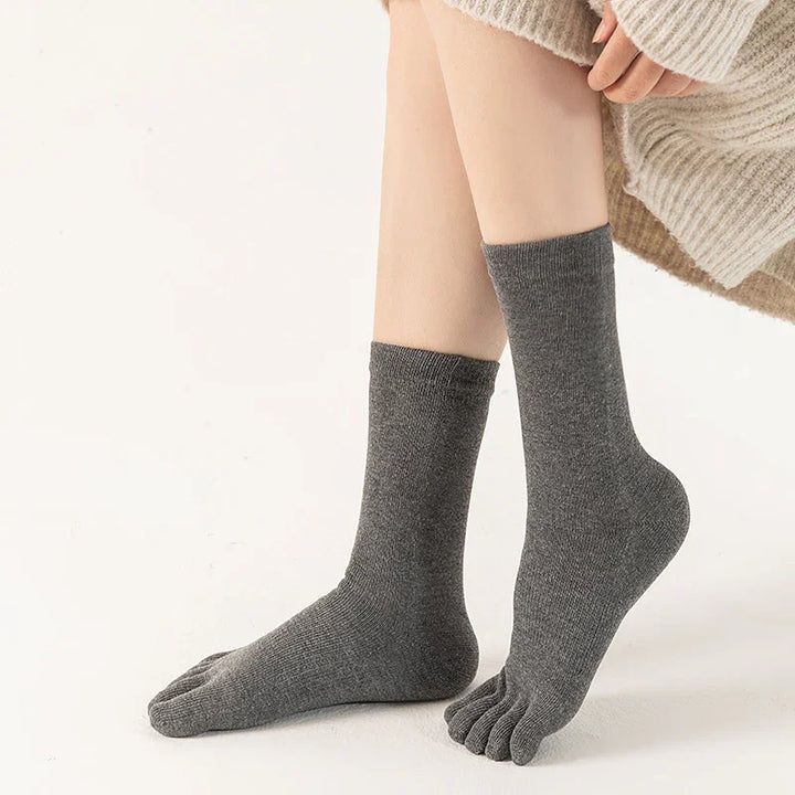 Person wearing gray toe socks with split toes sitting, beige sweater visible