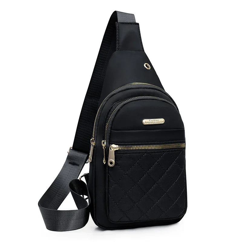 Black quilted sling bag with gold zippers and adjustable strap on white background