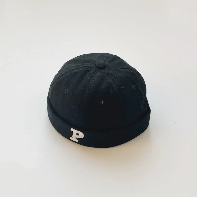 Black beanie cap with a white embroidered letter P on the front, displayed on plain white background