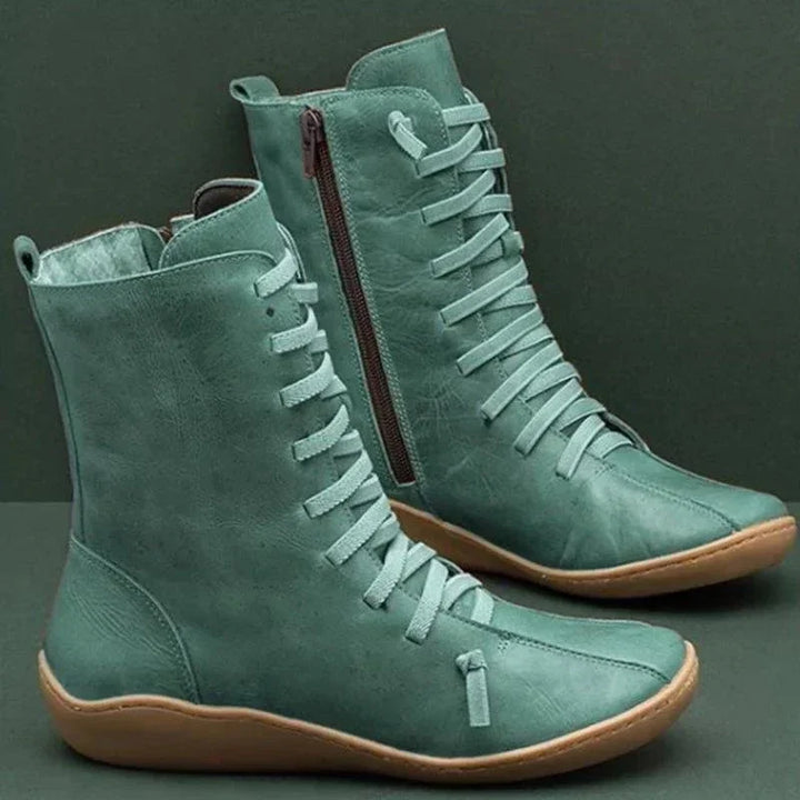 Pair of teal leather lace-up ankle boots with side zipper and tan rubber soles on dark background