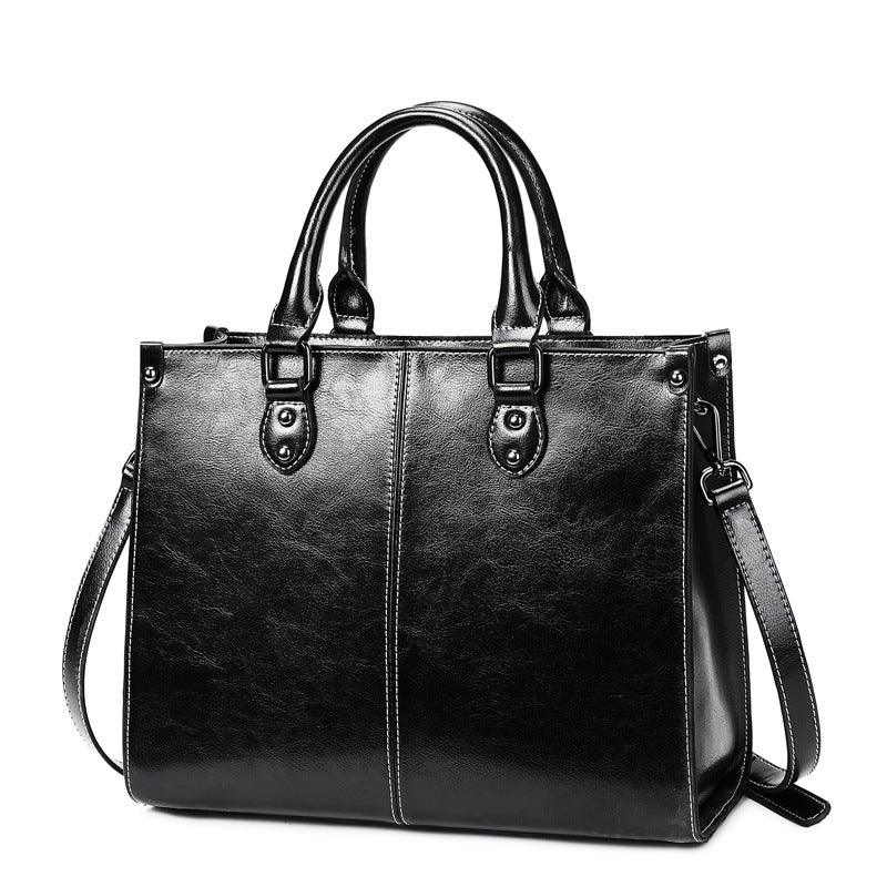 Black leather handbag with double handles and detachable shoulder strap on white background